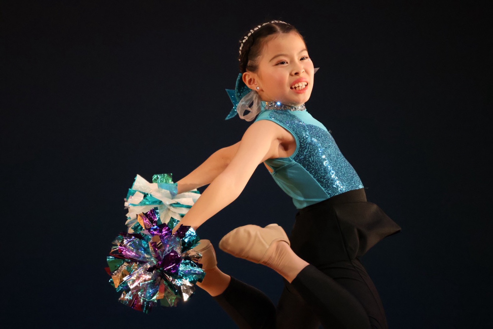 水色の衣装でポンポンを持ち力強く踊るダンサー
